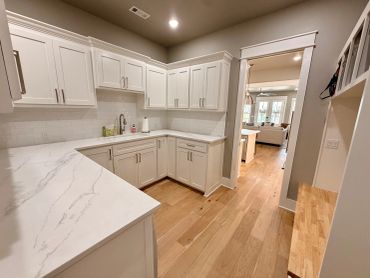 Bright kitchen with white cabinets and marble countertops.
