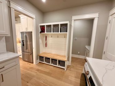 Organized mudroom area with storage bins, hooks, and bench.