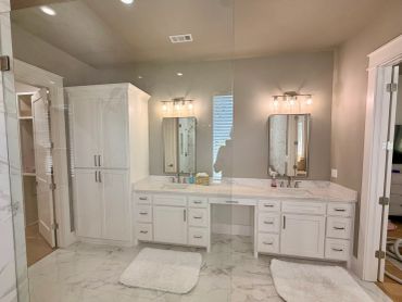 Bright modern bathroom with double sinks and white cabinetry.