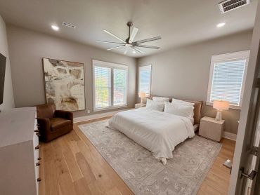 Cozy bedroom with large ceiling fan and brown leather chair.