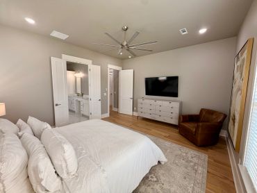 Modern bedroom with large ceiling fan, TV, and cozy leather chair.