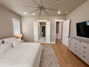 Modern bedroom with wooden flooring and large ceiling fan.