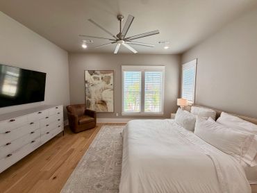 Modern bedroom with large ceiling fan and cozy seating area.