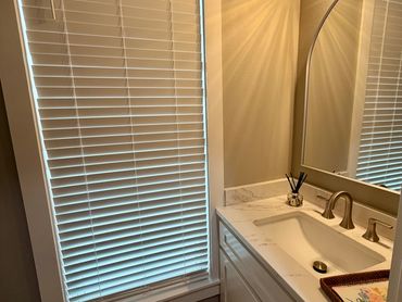 Bathroom corner with a window, sink, and mirror.