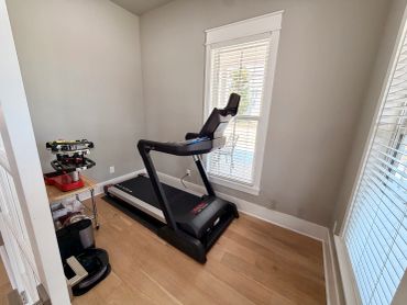 Home gym with a treadmill against a window.