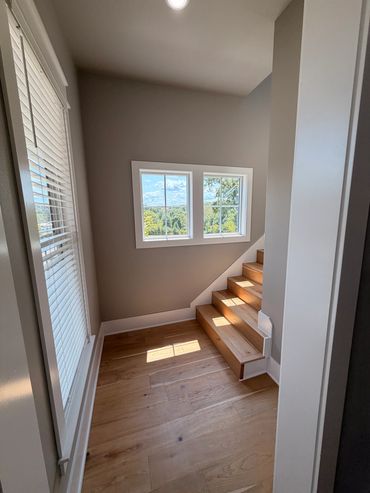 Bright stairwell with wooden stairs and windows.
