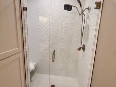 Minimalist shower with glass door and white tiles.