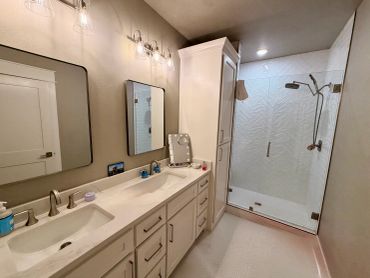 Modern bathroom with dual sinks and walk-in shower.
