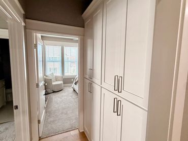 Hallway with white cabinets and a view into a bedroom.
