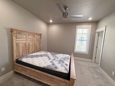 Cozy bedroom with wooden bed frame and ceiling fan.