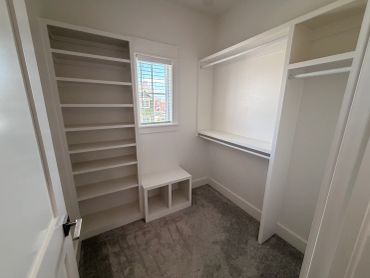 Empty walk-in closet with white shelving and a window.