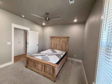 Simple bedroom with wooden bed and ceiling fan.