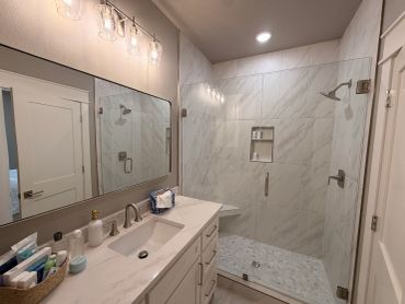 Modern bathroom with glass shower and marble accents.