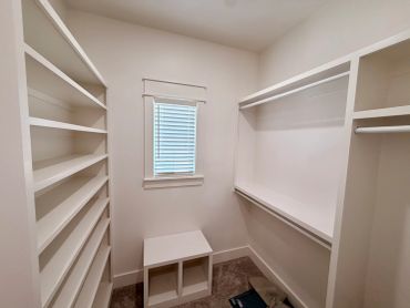 Empty walk-in closet with shelves and hanging rods.