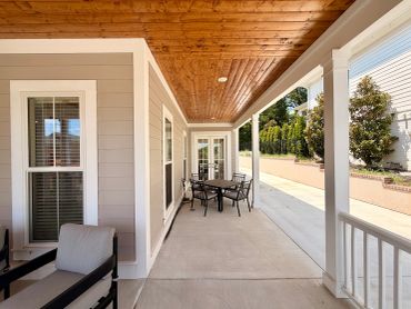 Covered porch with wooden ceiling and outdoor furniture.