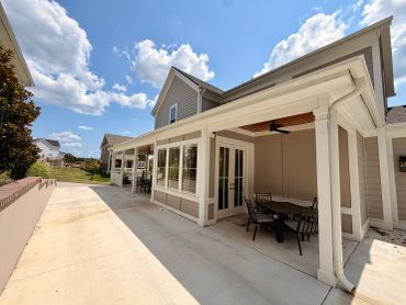 House patio with table and chairs under covered porch on a sunny day.