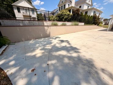 Wide driveway with shadowed tree and tire tracks.