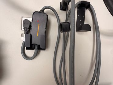 EV charger plugged into wall outlet with coiled cable.