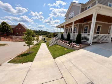 House with a porch and sidewalk on a sunny day.