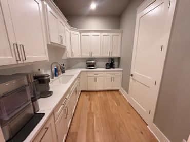 Modern kitchen with white cabinets and wooden floor.