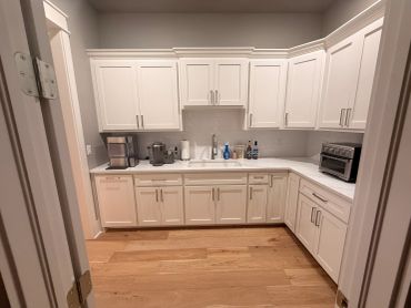 Modern white kitchen with wooden flooring.