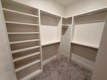 Empty walk-in closet with shelves and hanging rods.