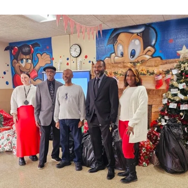 Five people posing indoors with Christmas decorations and murals in the background.