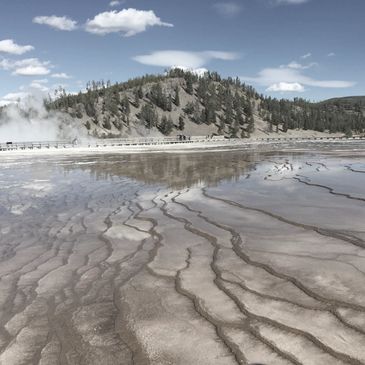 Yellowstone National Park, geyser steam in the distance  with hills and wetlands in the foreground