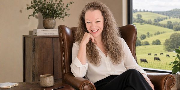 Woman smiling while sitting in a leather chair by a window.