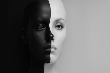 A face split into black and white halves, one eye closed, the other open.