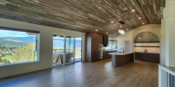 Modern kitchen with wooden ceiling and large windows.