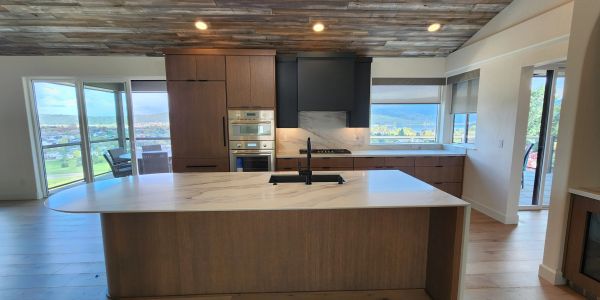Modern kitchen with wood accents and large windows.