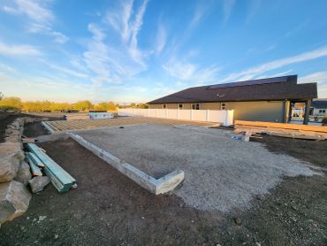 Construction site with foundation and wood framing next to a house.