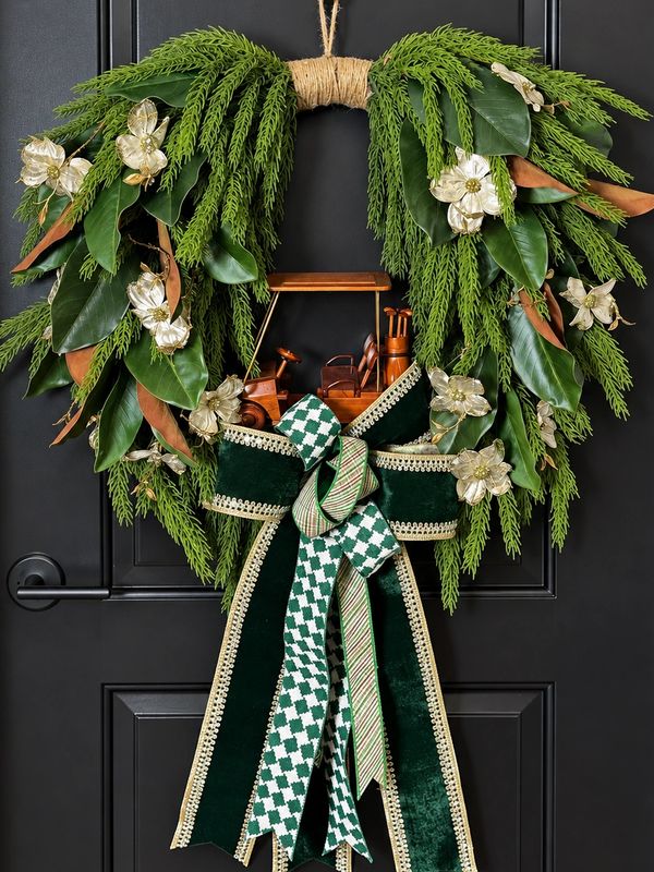 Green Christmas wreath with bow and wooden golf cart decoration.