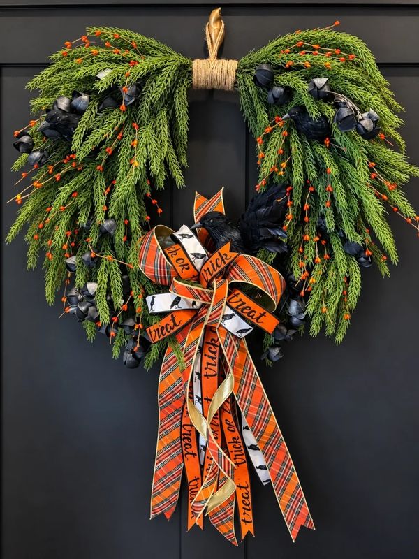 Halloween-themed heart-shaped wreath with festive ribbons and greenery.