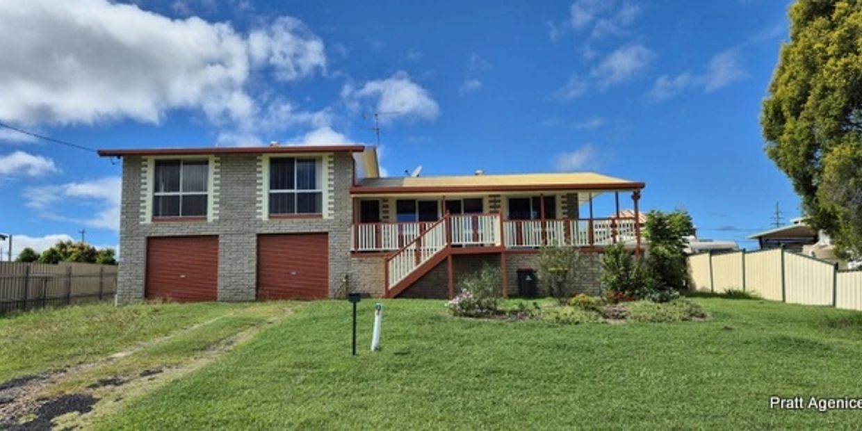 Two-story brick house with double garage and front porch under a blue sky.
