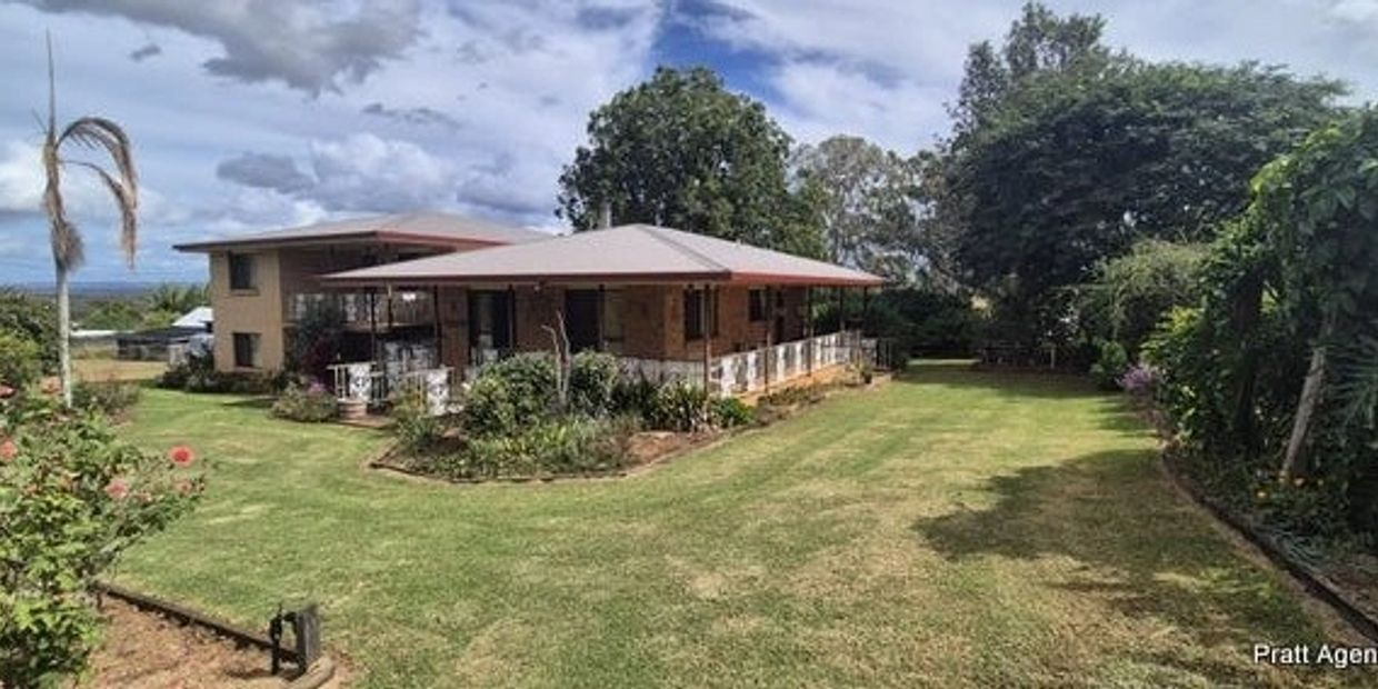 Spacious house with a large green lawn and garden under a partly cloudy sky.