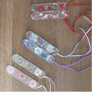Colorful floral bookmarks with ribbons on a wooden surface.