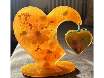 Orange resin heart with embedded flowers and a small hanging heart with a dog photo.