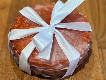 Stack of orange resin coasters tied with a white ribbon on a wooden surface.