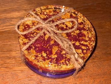 Round decorative item with gold flakes and twine bow on wooden surface.