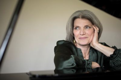 A thoughtful woman rests her head on her hand, looking away.