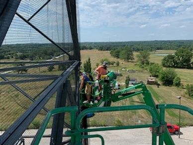 2 guys working on a lift securing the net using cables