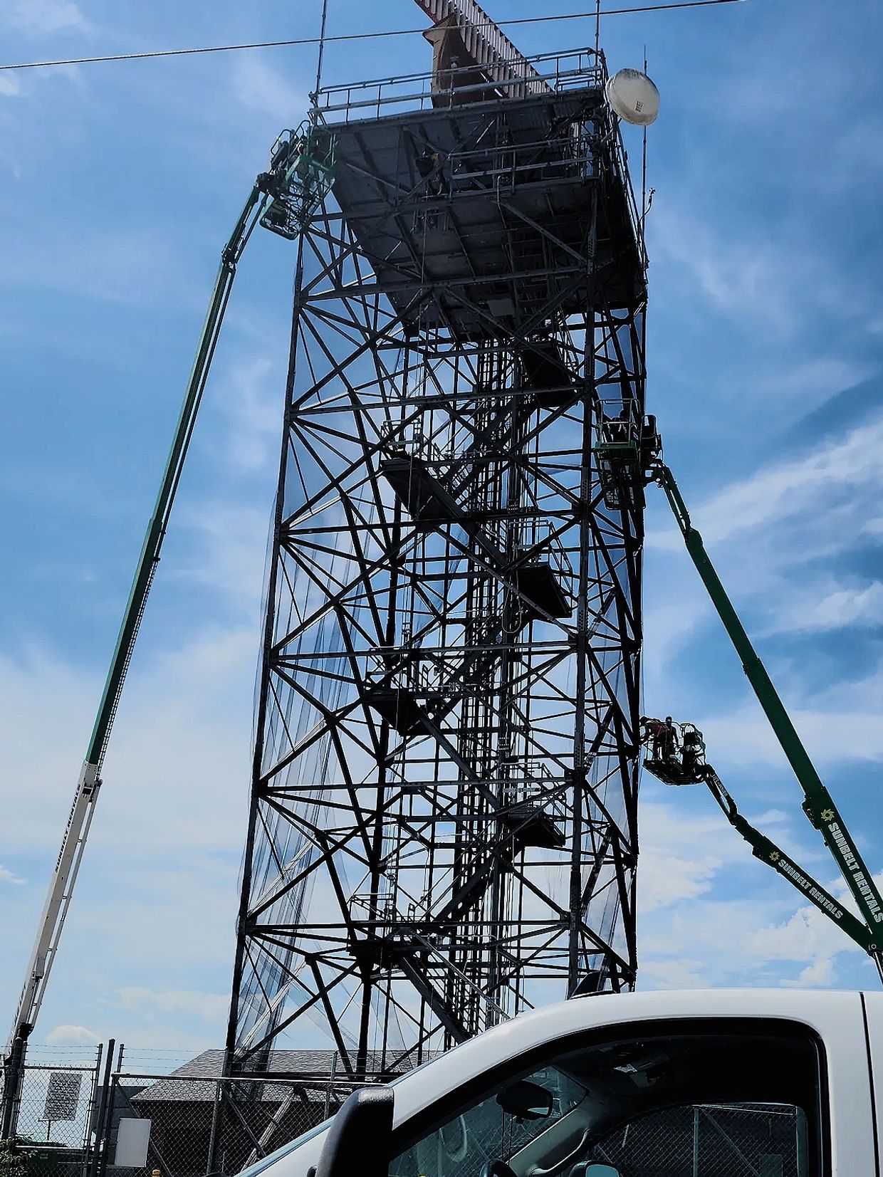 3 aerial boom lifts and guys up working on this bird netting tower job