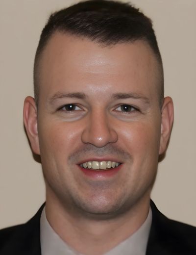 Smiling man with short hair in formal attire.