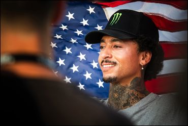 Nyjah Huston celebrating victory in front of an American Flag at the World Skateboard Tour Olympic Q