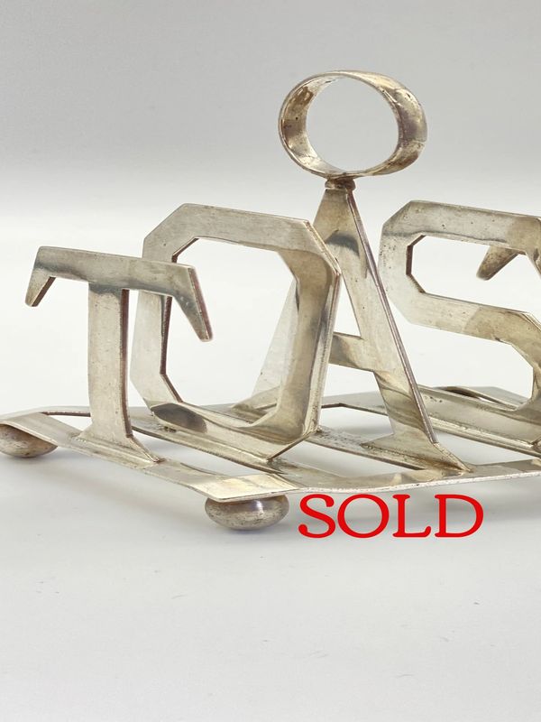 Silver plated toast rack spelling the word TOAST