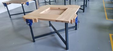 Woodworking clamps attached to a wooden frame on a metal stand.