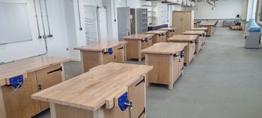 Empty woodworking workshop with wooden benches and blue clamps.