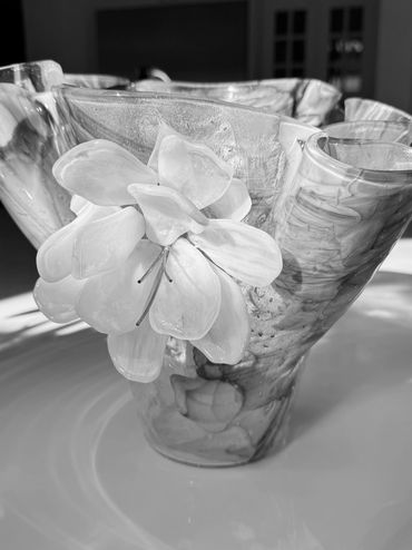 Elegant glass vase with a delicate white flower design, shimmering in soft light.